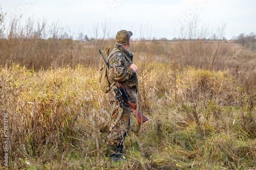 Hunter in camouflage with rifle. Winter hunting.