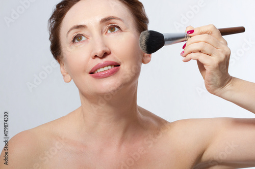 Makeup. Middle age woman with wrinkles applying make-up. Cosmetic. Base for make-up. Menopause.