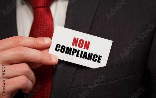 Businessman putting a card with text NON COMPLIANCE in the pocket photo