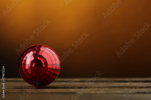 Palla di natale color rosso sopra superficie in legno  su sfondo arancio photo