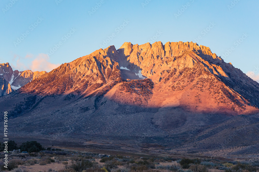 Early morning sunrise in fall hits the mountains of the eastern Sierra Nevada near Bishop, California