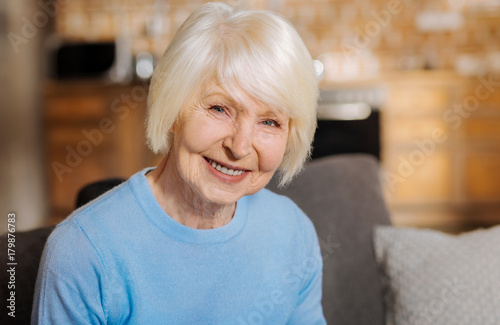 Wonderful mood. Portrait of a happy delighted elderly woman smiling and looking at you while being in a wonderful mood