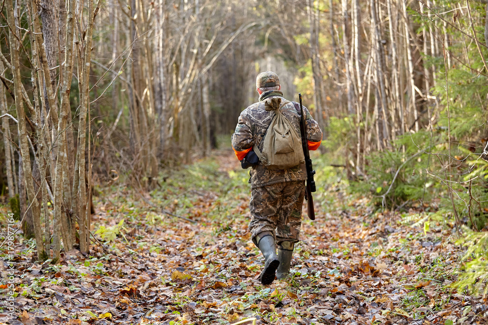 Hunter in camouflage clothes with hunting rifle during a winter hunting