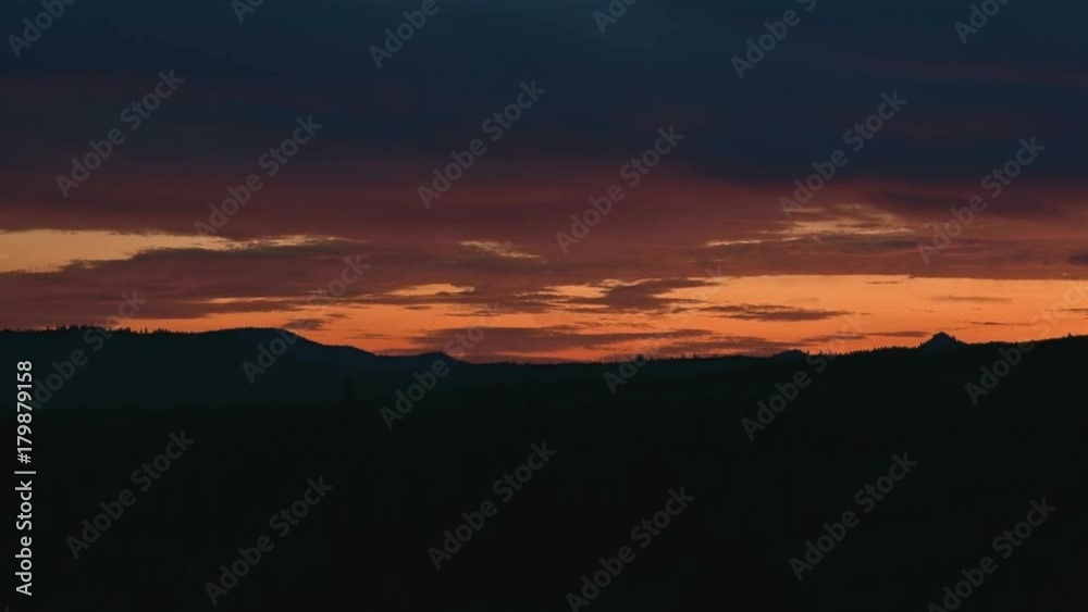 Orange cloudy dawn over silhouette of landscape