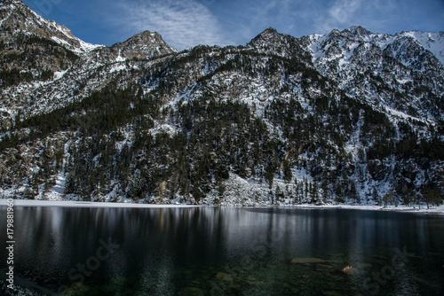 Mountain in afternoon light reflected in calm waters of lake