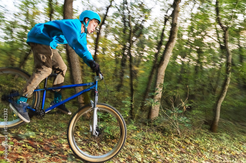 a young guy in a helmet flies landed on a bicycle after jumping from a kicker