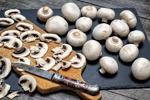 Fresh white mushrooms on a stone background.Champignons de Paris cut in pieces. photo