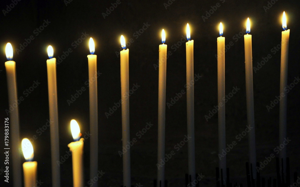 Poster, Print Lange schmale Kerzen erhellen die Dunkelheit einer Kirche, 40x26.7 cm
