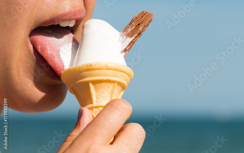 A woman licks a soft white mr whippy ice cream with a flake on a hot summer day photo