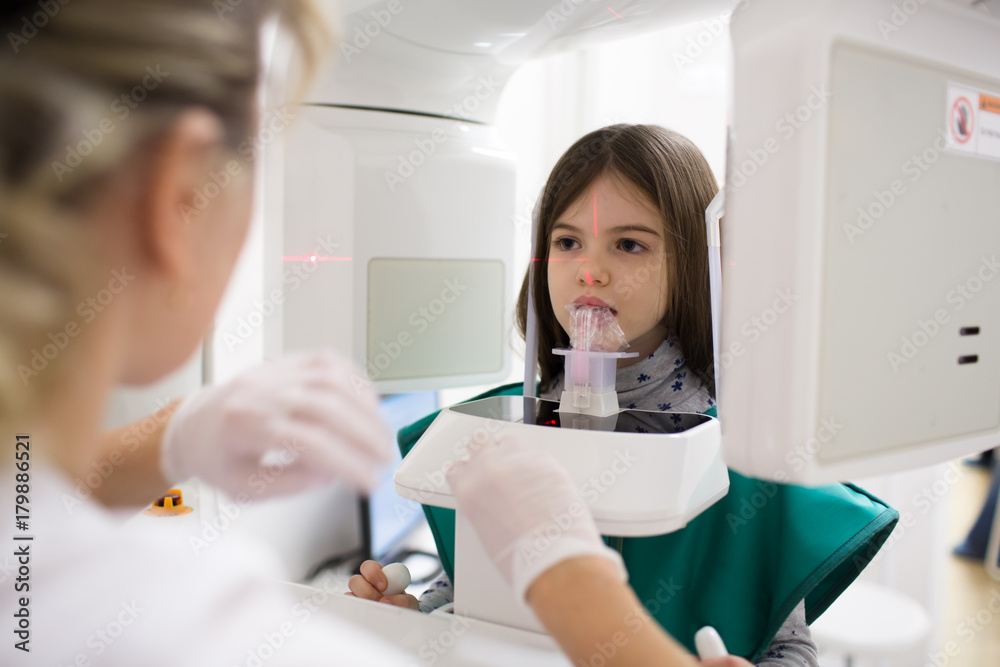 doctor makes a panoramic x-ray of teeth to a girl in a dental office doctor makes a panoramic x-ray of teeth to a girl in a dental office