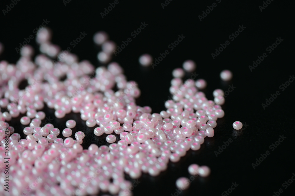 Pink seed beads scattered on a dark surface Pink seed beads scattered on a dark surface