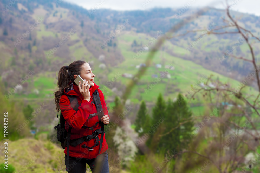 Young smiling tourist woman with phone in the mountains
