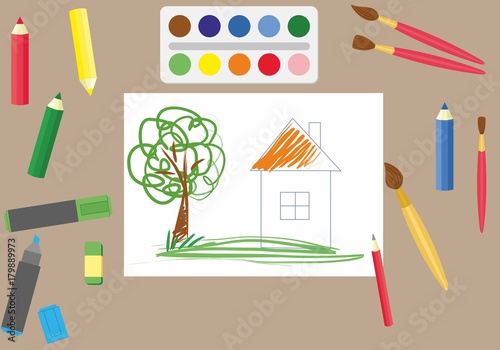 Colorful pencils and brushes lying around scketchbook with kids crayon drawing of home, cloud, tree and sun