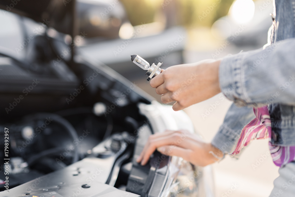 Woman replacing a broken headlight bulb