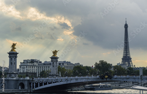 Eiffel tower and Alexandre III bridge close to the Seine river, Paris symbol and iconic landmark in France, on a cloudy day. Famous touristic places and romantic travel destinations in Europe