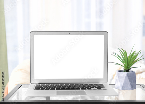 Modern laptop with blank screen on table at home