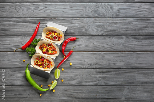 Holder with delicious tacos and chili con carne on wooden background