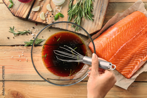 Woman preparing soy marinade for salmon on wooden table