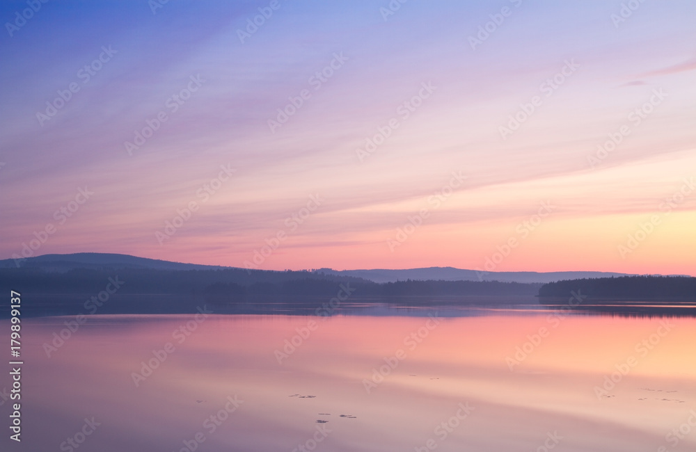 Colourful summer sunset reflecting in calm a lake