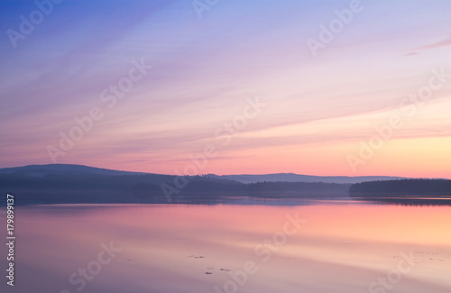 Colourful summer sunset reflecting in calm a lake © robin