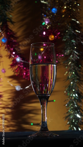 A champagne glass stands on the table. The photo on the background of Christmas light.