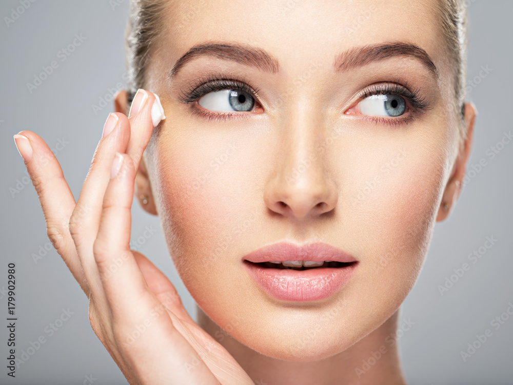 Beautiful young woman gets cream near eyes Beautiful young woman gets cream near eyes