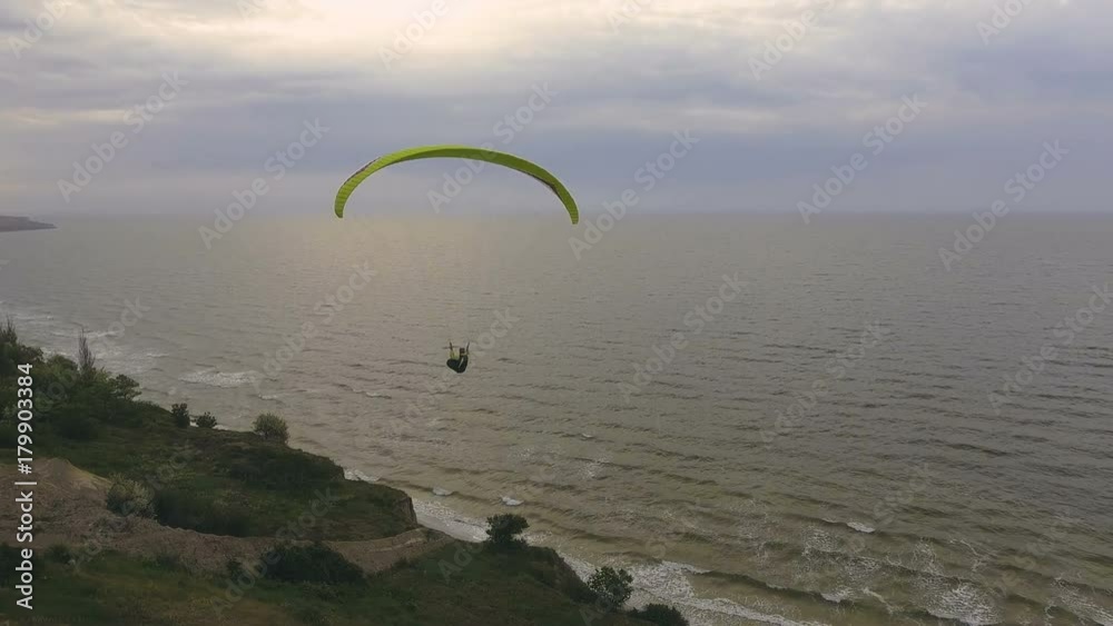 Paraplane, paraglider in the air aerial shot. Extreme man flies on a paraglider over a cliff near the sea. Extreme life. Paraplane, paraglider in the air aerial shot. Extreme man flies on a paraglider over a cliff near the sea. Extreme life.