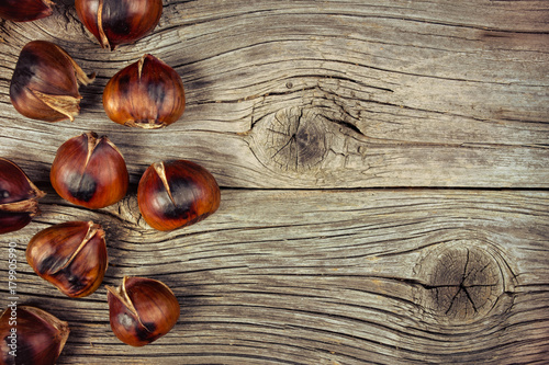 Roasted chestnuts on old wooden background
