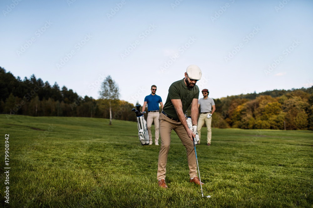 Golf player walking and carrying bag on course during summer game golfing