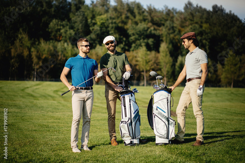 Golf player walking and carrying bag on course during summer game golfing