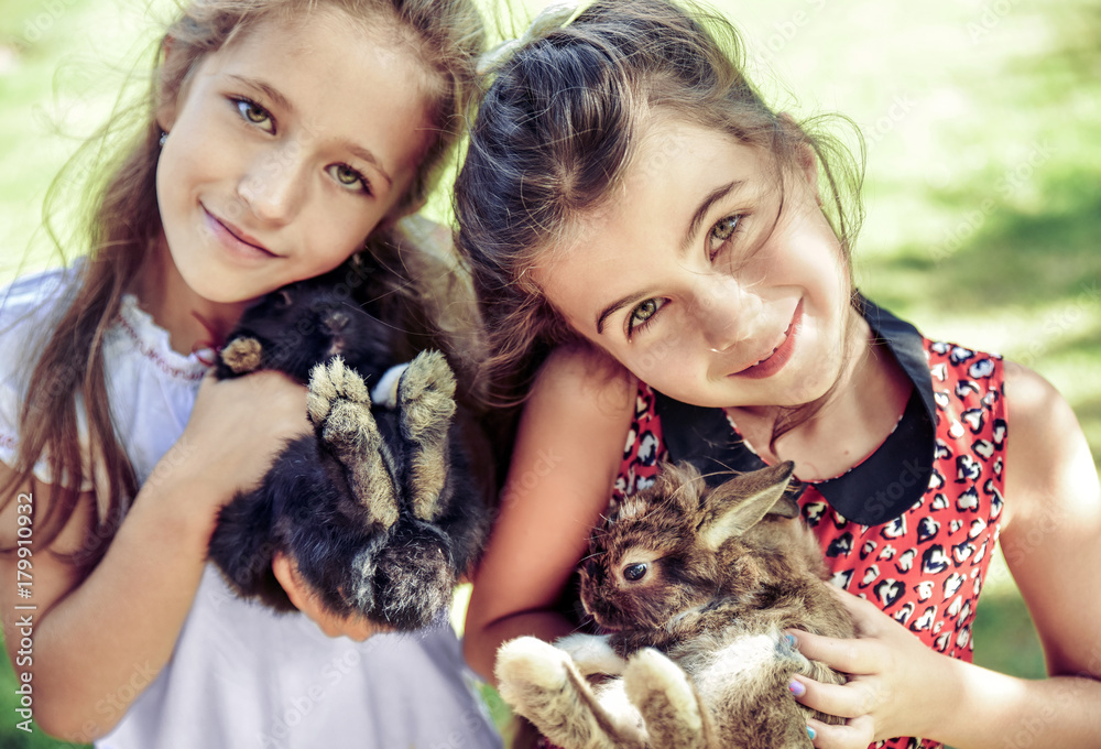 Two cheerful girls hugging fluffy bunnies