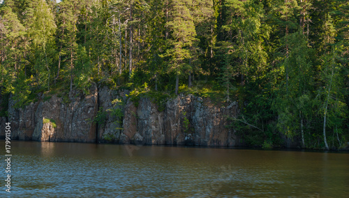 The rocky coast of the river with rocks growing on trees photo