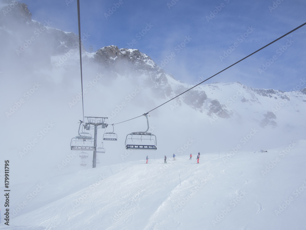 Chair lifts, skiers, and mountain peaks emerge from the fog Chair lifts, skiers, and mountain peaks emerge from the fog