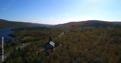 Arctic church, Cinema 4k aerial view over utsjoki church, near mantojarvi lake and utsjoki town, on a sunny autumn day, in Lapland, Lappi, Finland photo