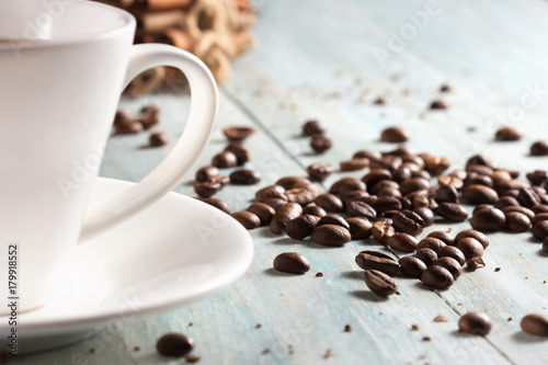 Coffee cup with coffee beans on wooden boards close-up