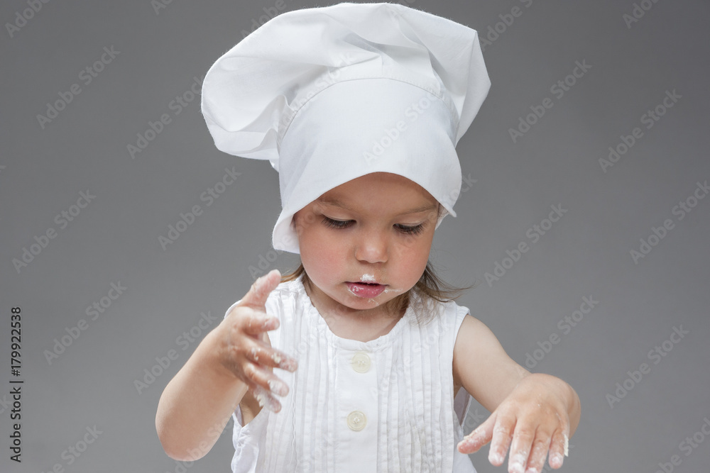 Cooking Ideas. Portrait of Caucasian Little Girl in Cook Uniform Posing with Smudgy Face Against Gray Background. Cooking Ideas. Portrait of Caucasian Little Girl in Cook Uniform Posing with Smudgy Face Against Gray Background.