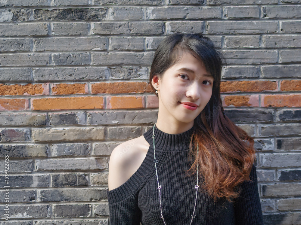 Portrait of beautiful young Chinese woman wearing black tube dress in Shanghai Xintiandi, she smiling on gray brick background, happy time , Asian girl Concept ,Travel Concept. Portrait of beautiful young Chinese woman wearing black tube dress in Shanghai Xintiandi, she smiling on gray brick background, happy time , Asian girl Concept ,Travel Concept.