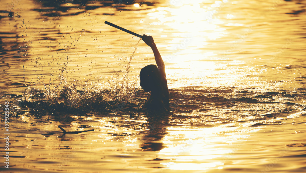 The boys are playing the water in the sunset - obrazy, fototapety, plakaty 