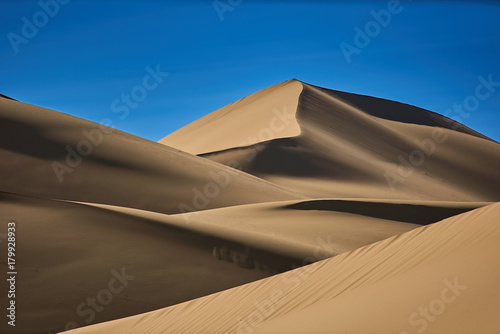 Fototapeta Naklejka Na Ścianę i Meble -  Smooth sand dunes in the desert, warm dry sand and blue sky