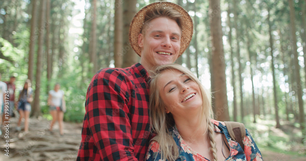 Portrait of beautiful caucasian couple spending time in a forest during sunny day. Smiling couple  relaxing in woods.