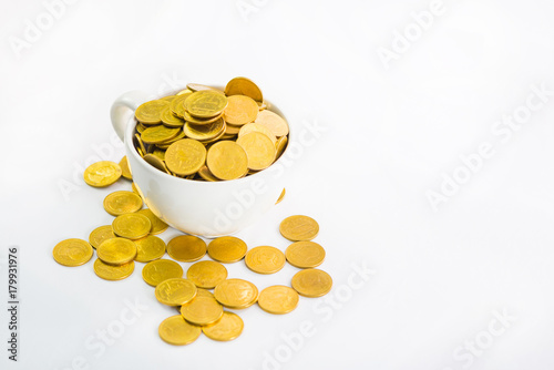 Golden coins in white cup of coffee on the white background.