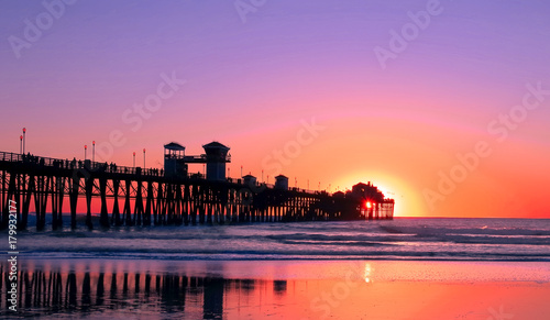 Beach at Sunset – colorful sunset with silhouette of boardwalk as ocean waves roll in