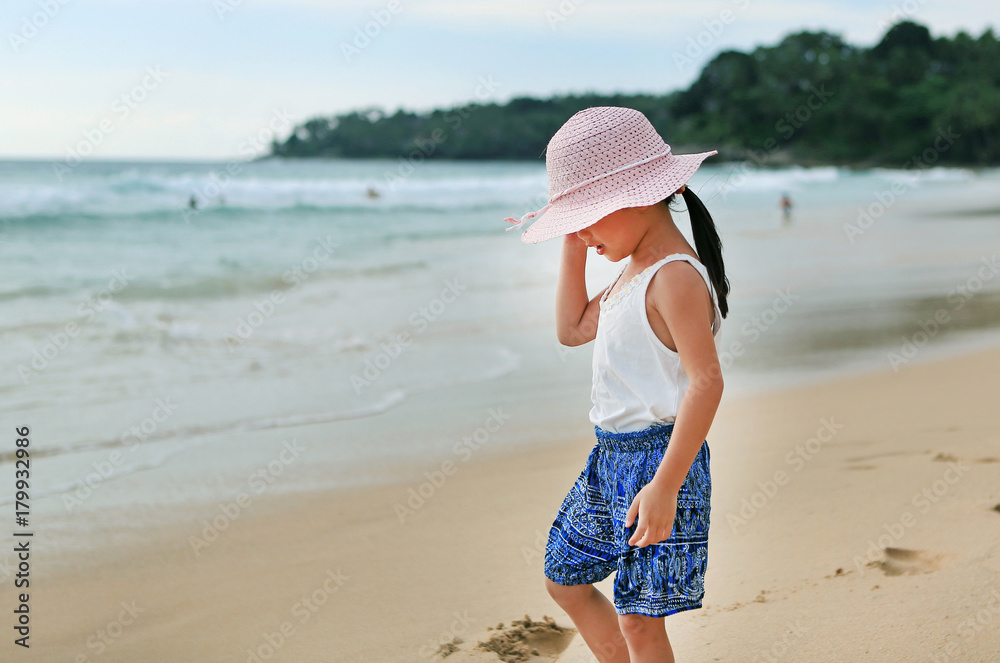Little asian girl wear straw hat walking on the beach. Little asian girl wear straw hat walking on the beach.