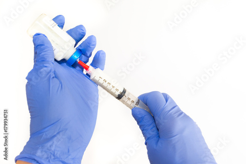 Right Handed Anesthesiologist Withdrawing Propofol into a Syringe. The doctor is wearing non-sterile blue gloves. 
