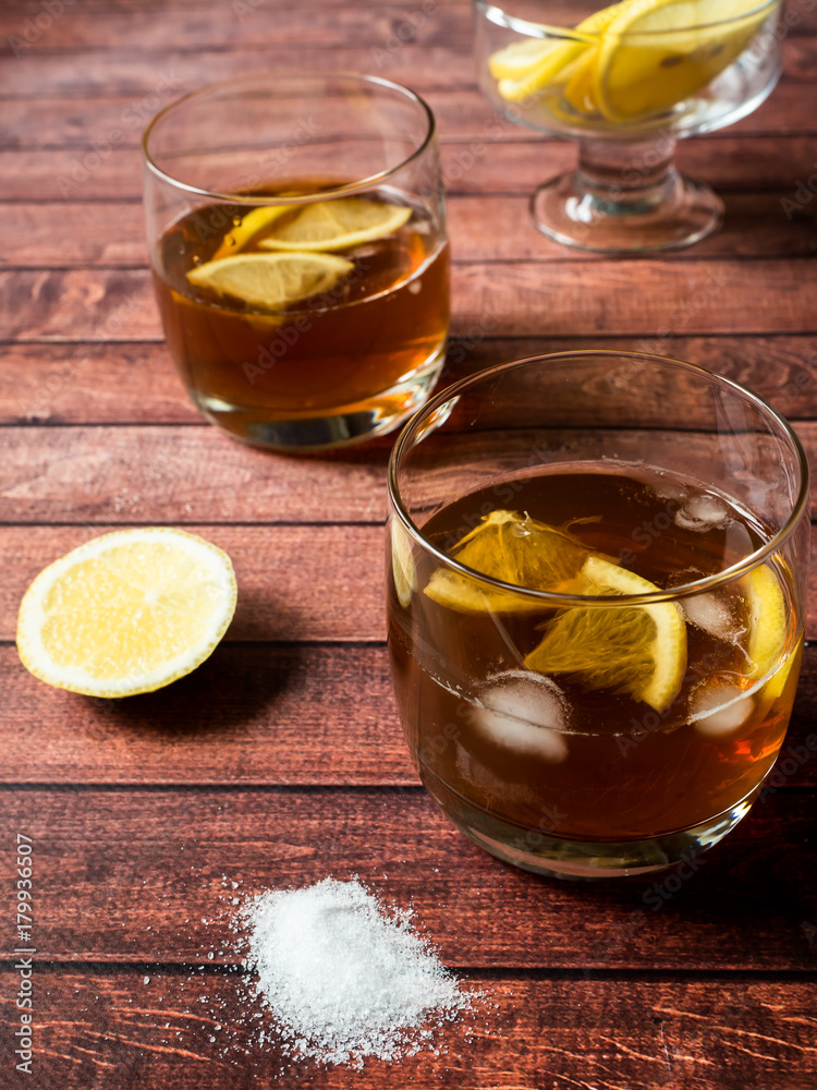 Glasses of cocktail with ice and lemon on wooden table close-up Glasses of cocktail with ice and lemon on wooden table close-up