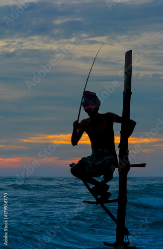 Silhouettes of the traditional Sri Lankan stilt fishermen at the sunset in Koggala, Sri Lanka. Stilt fishing is a method of fishing unique to the island country of Sri Lanka photo