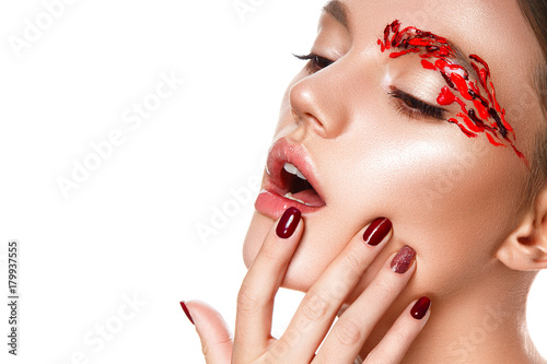 Beautiful woman portrait with red art on face.