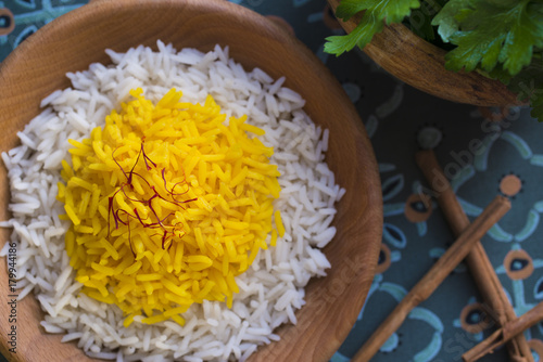 Rice cooked with saffron in a wooden bowl with fresh parsley for garnish