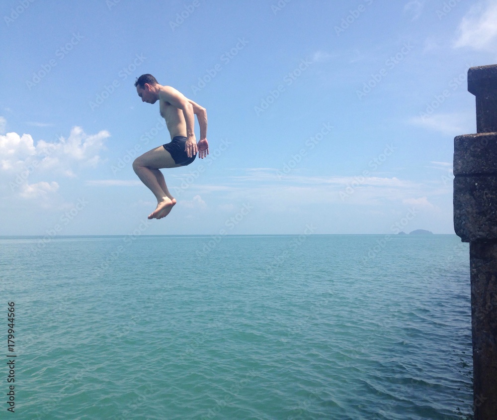 man jumping to water of sea