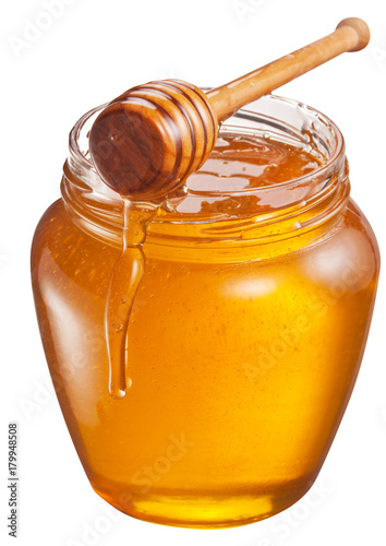 Jar full of fresh honey and honey dipper. File contains clipping path.